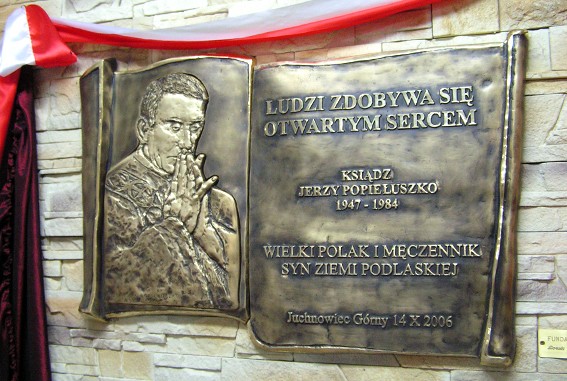 Tablica pamiątkowa ku czci patrona szkoły w Juchnowcu - Ks. Jerzego Popiełuszki; odlew mosiężny, oksydowany